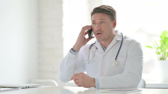 Male Doctor Talking on Phone in Office