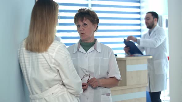 Two Nurses Talking Near Reception Desk