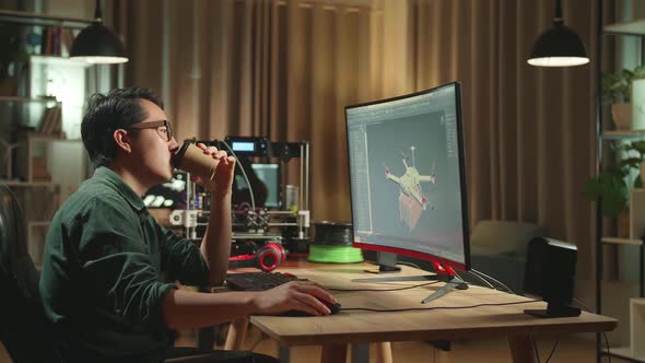 Asian Engineer Drinking Coffee While Work On Personal Computer And 3D Printer