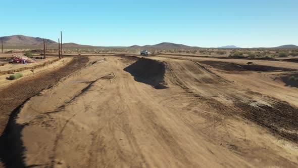 Flying over a dirt motocross racetrack as a water truck sprays the dirt surface