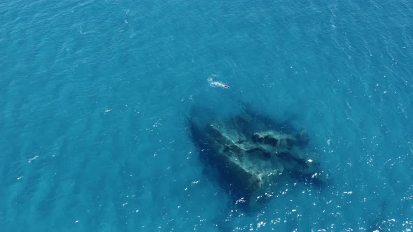 Aerial view of a ship wreck in the ocean. Boy snorkels near submerged ship wreck