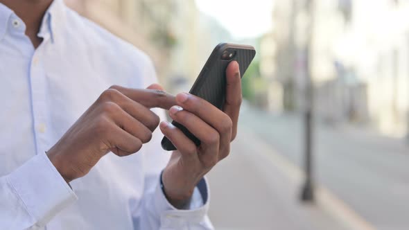 Close Up of Hands of African Man Using Smartphone