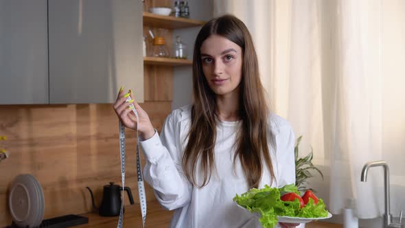 Healthy Fit Girl with Measuring Tape and Vegetables in the Kitchen