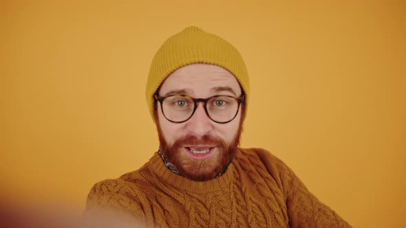 Young Bearded Caucasian Man Talks Smiles Shows Thumb Up and Sign of Freedom and Peace Points Finger