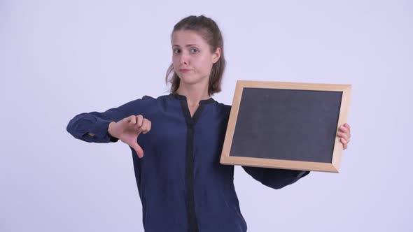 Young Serious Businesswoman Holding Blackboard and Giving Thumbs Down