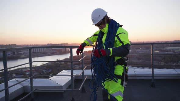 Climber Tries to Untangle Safety Ropes on Roof at Sunset