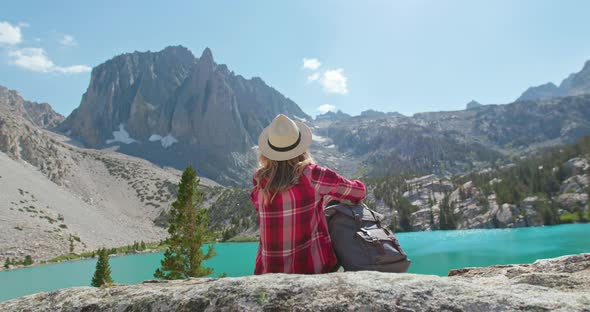 Back View of Traveler Girl Sitting with Scenic Lake and Mountain View, 