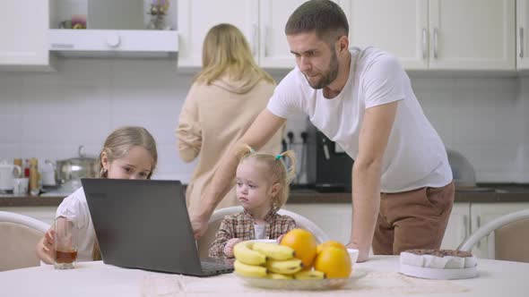 Handsome Man Turning on Cartoons on Laptop for Daughters at Home