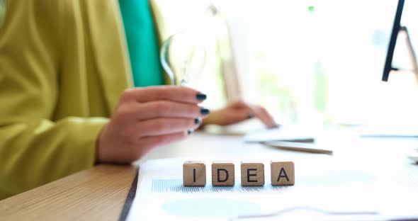 Closeup of Person Holding a Light Bulb Working at Computer