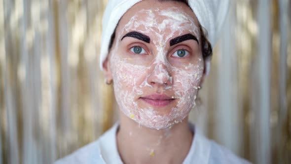 young woman with cosmetic mask on her face and with cosmetic paint on her eyebrows