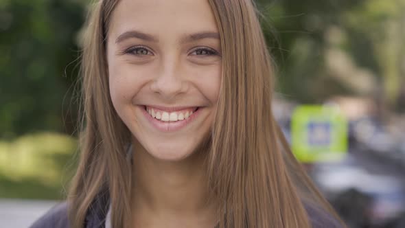 Close-up Portrait of Young Caucasian Woman with Long Hair Smiling Happily Looking at the Camera