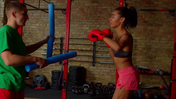 Determined Athletic Black Woman Boxer Practicing Combinations with Trainer