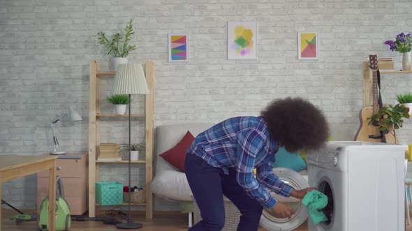 African American Housewife in Shirt Doing Homework Taking Out Washed Clothes at Home