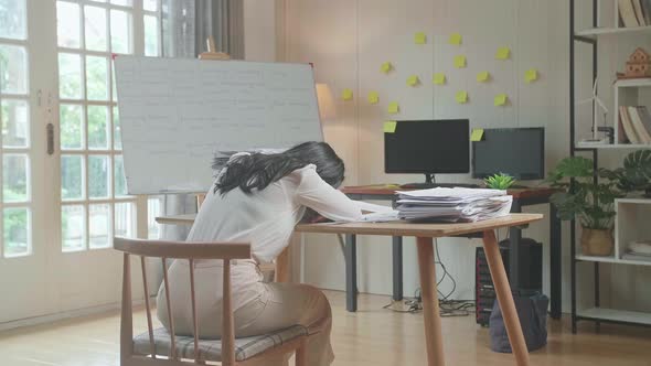 Back View Of Asian Woman Sleeping While Working Hard With Documents At The Office