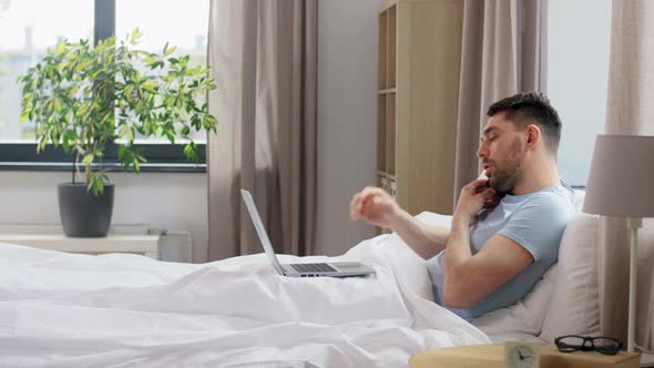 Man with Folder Calling on Phone in Bed at Home