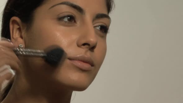 CU OF A YOUNG WOMAN APPLYING BLUSHER