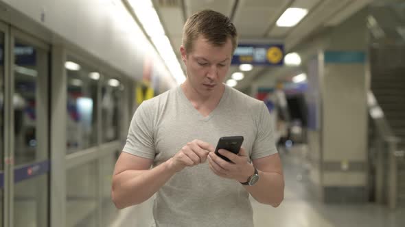 Young Happy Tourist Man Using Phone at the Underground Train Station in Bangkok