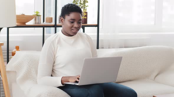 Afro American Woman Freelance Student Businesswoman Sitting on Couch at Home Using Computer App for