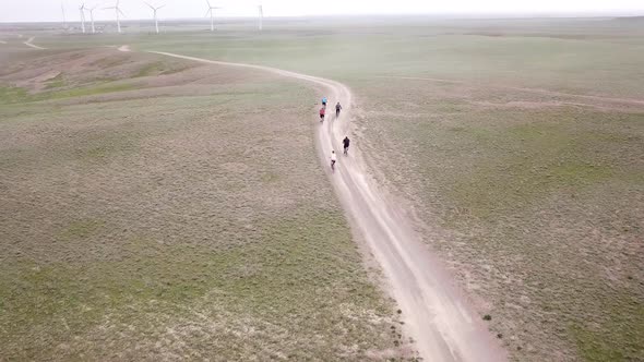 A Group of Cyclists Rides Along the Windmills