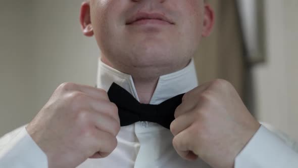 Groom Adjusts Bow Tie. Preparing To Go To the Bride. Businessman in White Shirt. Wedding Day