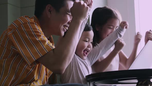 Happy family with kids enjoying using application on laptop together at home