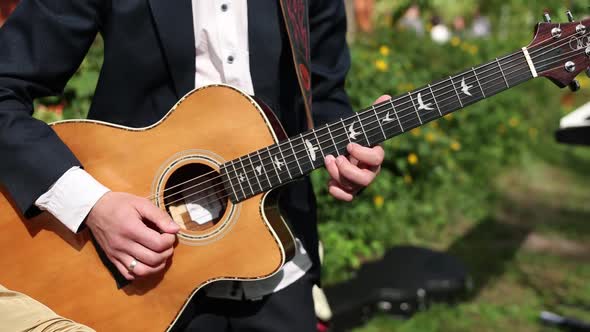 man playing guitar on the street in a jacket