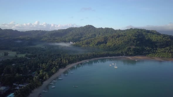 Aerial of calm fishing village on sunny morning in the Philippines - backwards tracking shot