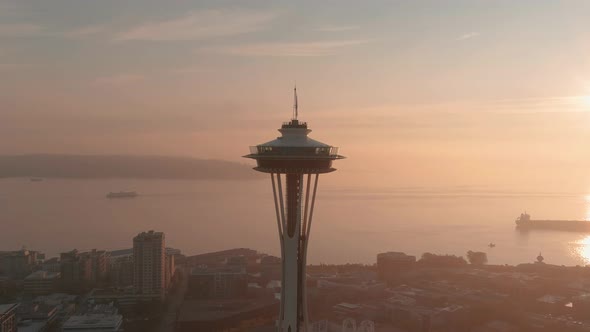 Orbiting aerial the Space Needle with a bright and smoke filled sunset over the Puget Sound in the b
