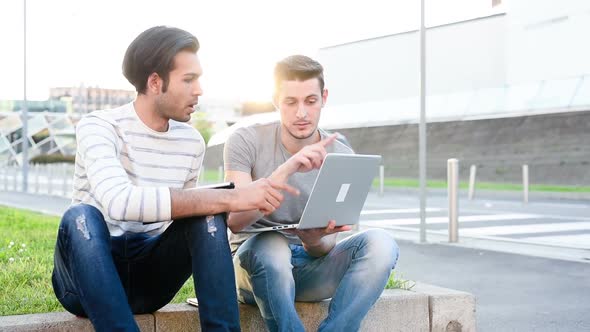 Two multiethnic men outdoor using pc and tablet