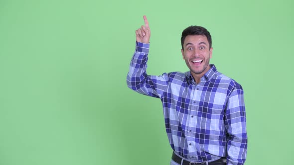 Happy Young Hispanic Man Pointing Up and Looking Excited