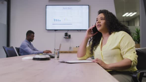 Happy diverse couple of business people working together, talking on smartphone in modern office