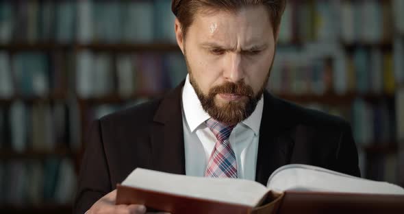 Bearded Man in Suit Reading Book in Library