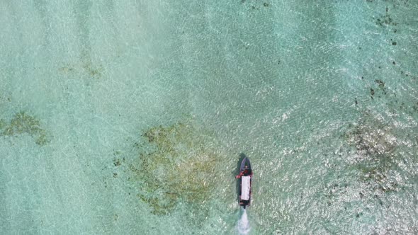 Motor boat cruising in shallow turquoise ocean waters against tide.