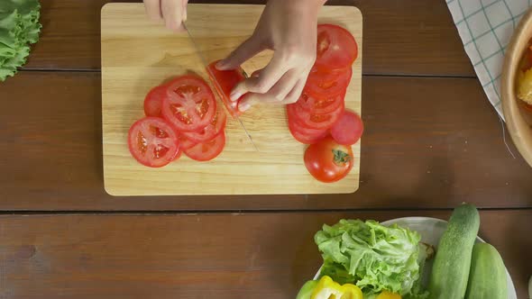 woman making salad healthy food and chopping tomato on cutting board in the kitchen.