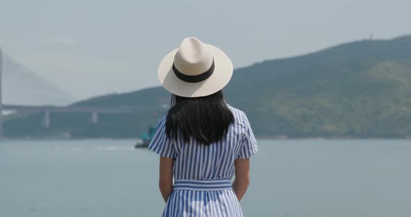 Woman look at the sea with straw hat