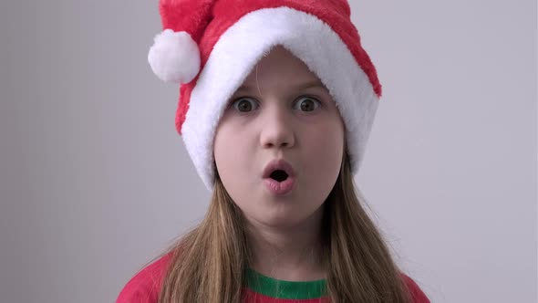 Close Up Surprised Christmas Girl in Santa Hat on White Background alt