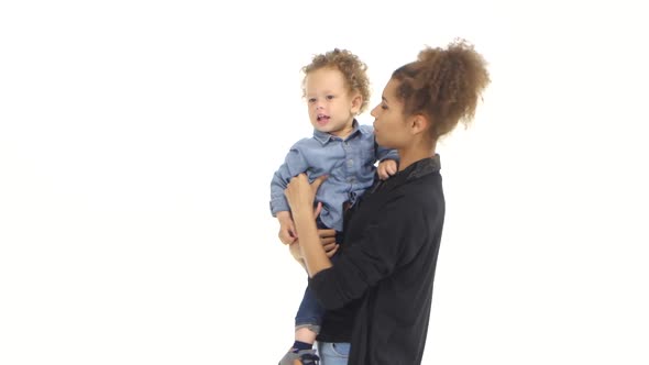 African American Mother Is Holding a Child and Playing with It. White Background