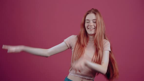 The 20Yearold Redhead Vesela is Having Fun in a Pink Casual Tshirt Isolated on a Pink Background