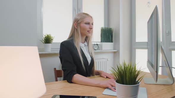 Smiling Business Woman Showing Thumbs Up. Cheerful Young Blond Female in Elegant Suit Sitting in