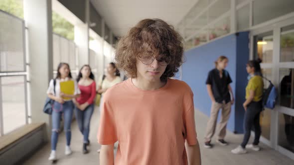 A Teenage Boy is Standing in the High School Hallways and Some Bullies Give Him a Shove