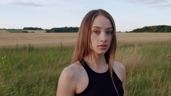 Portrait of Pretty Longhaired Young Sports Girl Looking at Camera at Field