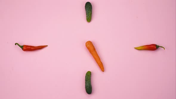 Stop Motion Clock From Colored Vegetables Moving Arrows From Carrots on a Pink Concrete Background