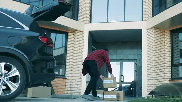 A Man Is Putting Together Parcels at the Doorstep of a Building