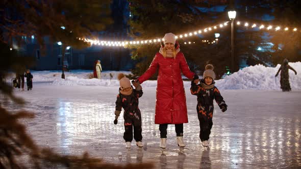 A Family of Young Mother and Two Kids Skating on the Decorated Ice Rink