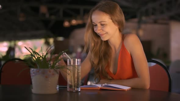 Blond Long Haired Lady Sits at Cafe Table Smiles