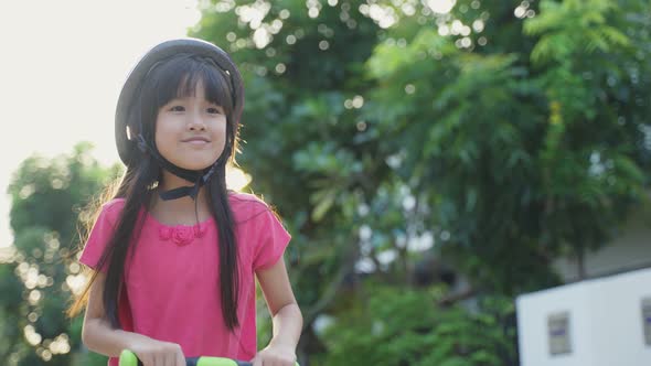 Development activity for children. Asian young girl kid playing small scooter riding on road outdoor