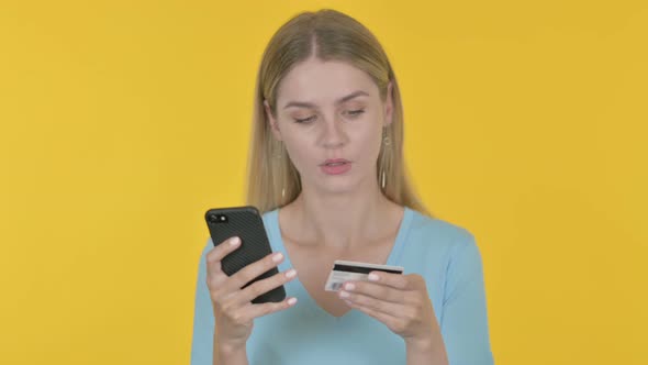 Young Woman Shopping Online via Smartphone on Yellow Background