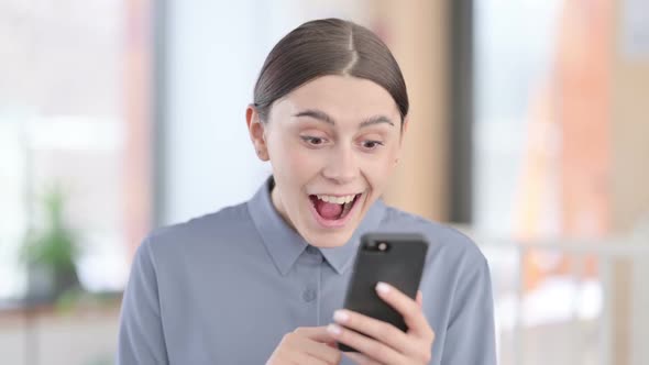 Portrait of Latin Woman Celebrating Success on Smartphone