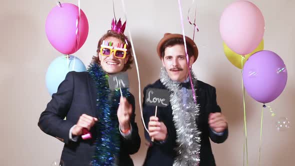 Two men holding boards in love in photo booth