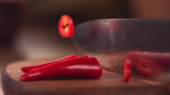 Knife Cutting Red Chilli Pepper on Wood in Slow Motion